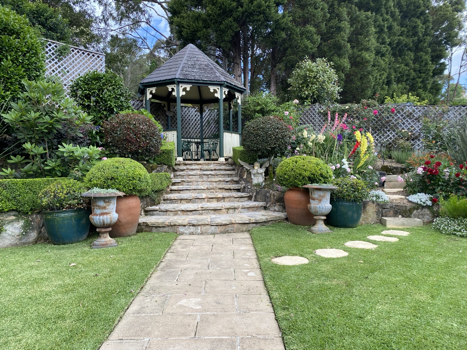 Rounded clipped shrubs framing a gazebo and colourful mature garden